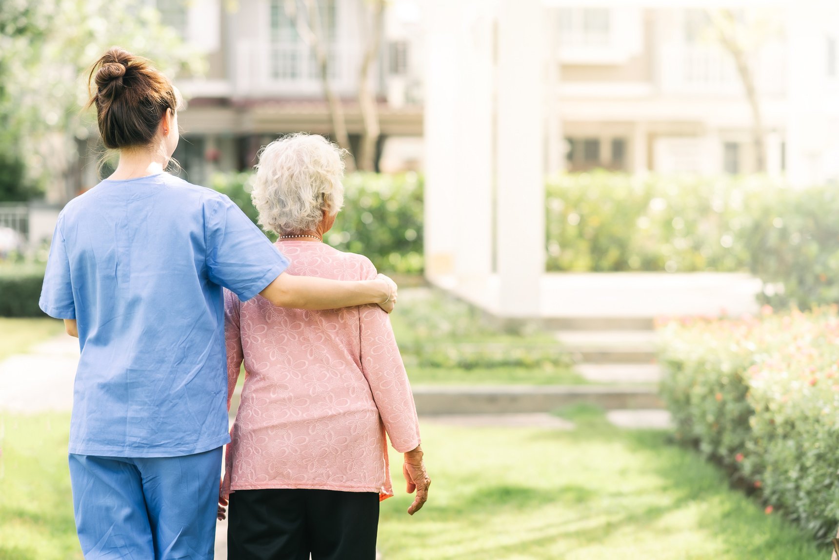 Caregiver Supporting an Elderly Woman as They Walk 