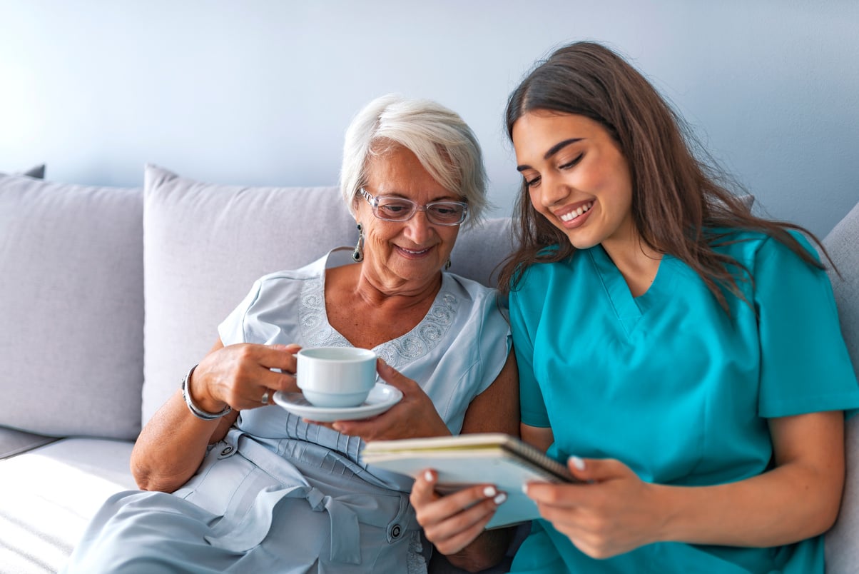 Young nurse spending time with happy elder patient in nursing home